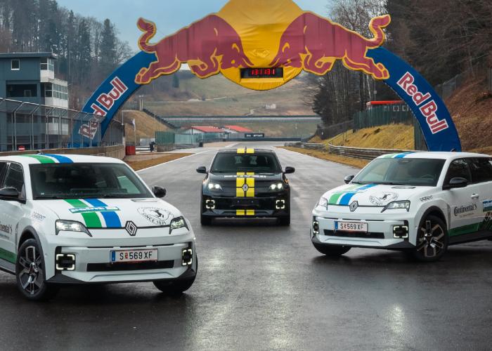 Drei sportliche Renault-Fahrzeuge stehen auf einer Rennstrecke unter einem Red Bull-Bogen. Zwei weiße Fahrzeuge mit grünen und blauen Akzenten tragen Logos von Sponsoren wie Continental und Point S, während das mittlere schwarze Auto gelbe Rennstreifen hat.